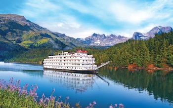 Luxury river cruise sailing with mountain and forest backdrop
